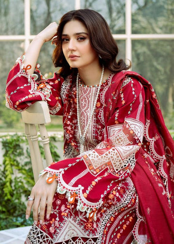 Woman in a red and white embroidered traditional outfit sitting outdoors.