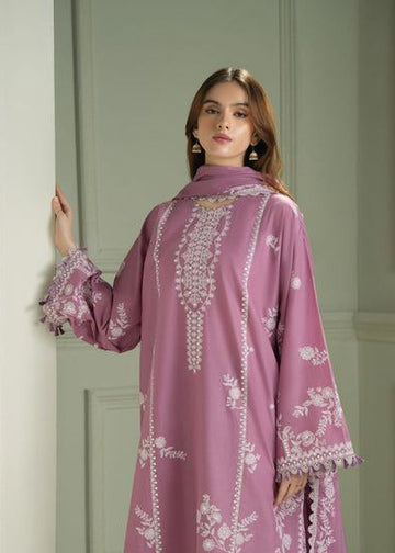 Woman wearing a pink embroidered outfit against a white wall